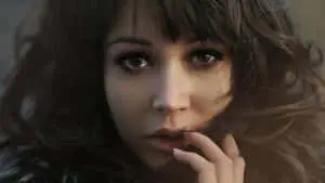 a woman with long hair is posing with her hand on her face