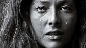 a woman is crying in front of a black and white photo