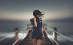 A young girl stands alone in a sun-filled day.