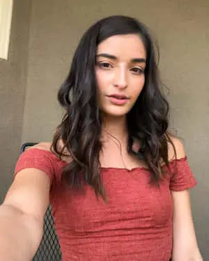 a woman in a red top and shorts is taking a selfie